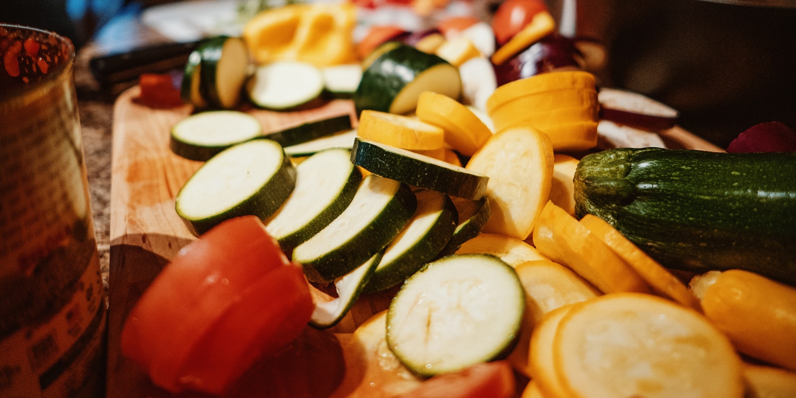 Kleurrijke plakjes courgette, pompoen en paprika op een houten snijplank